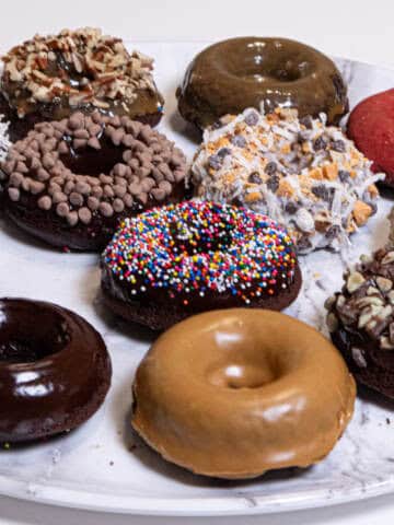 Chocolate Cake Donuts are featured with 12 different toppings sit on a marble platter.