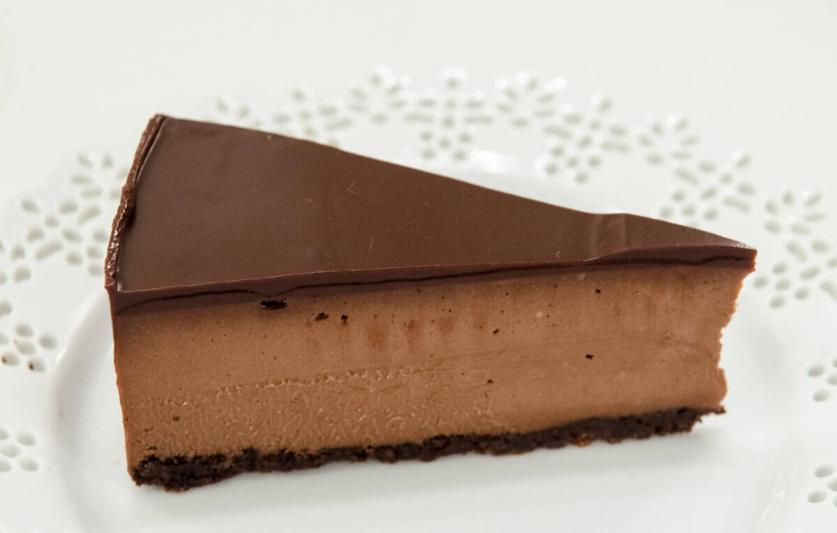 A slice of the Chocolate Cheesecake on a white lace plate.