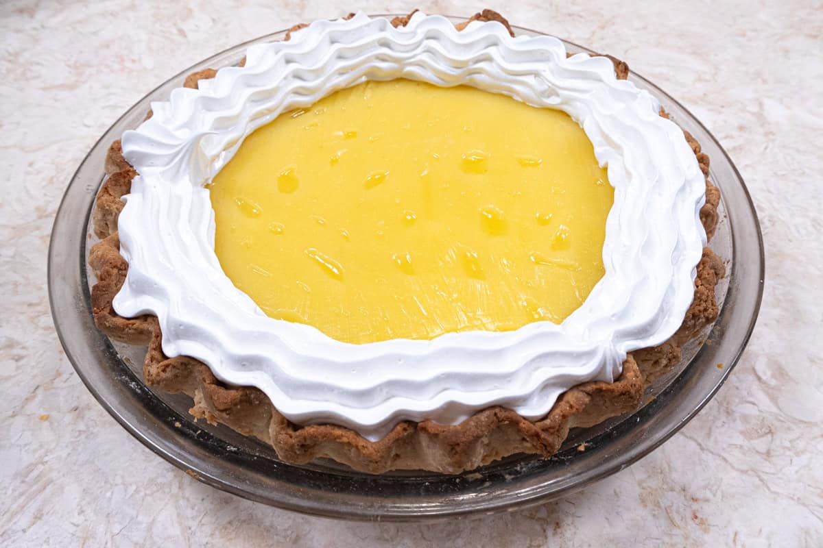 The meringue is piped around the edge of the pie touching the inside edge. 