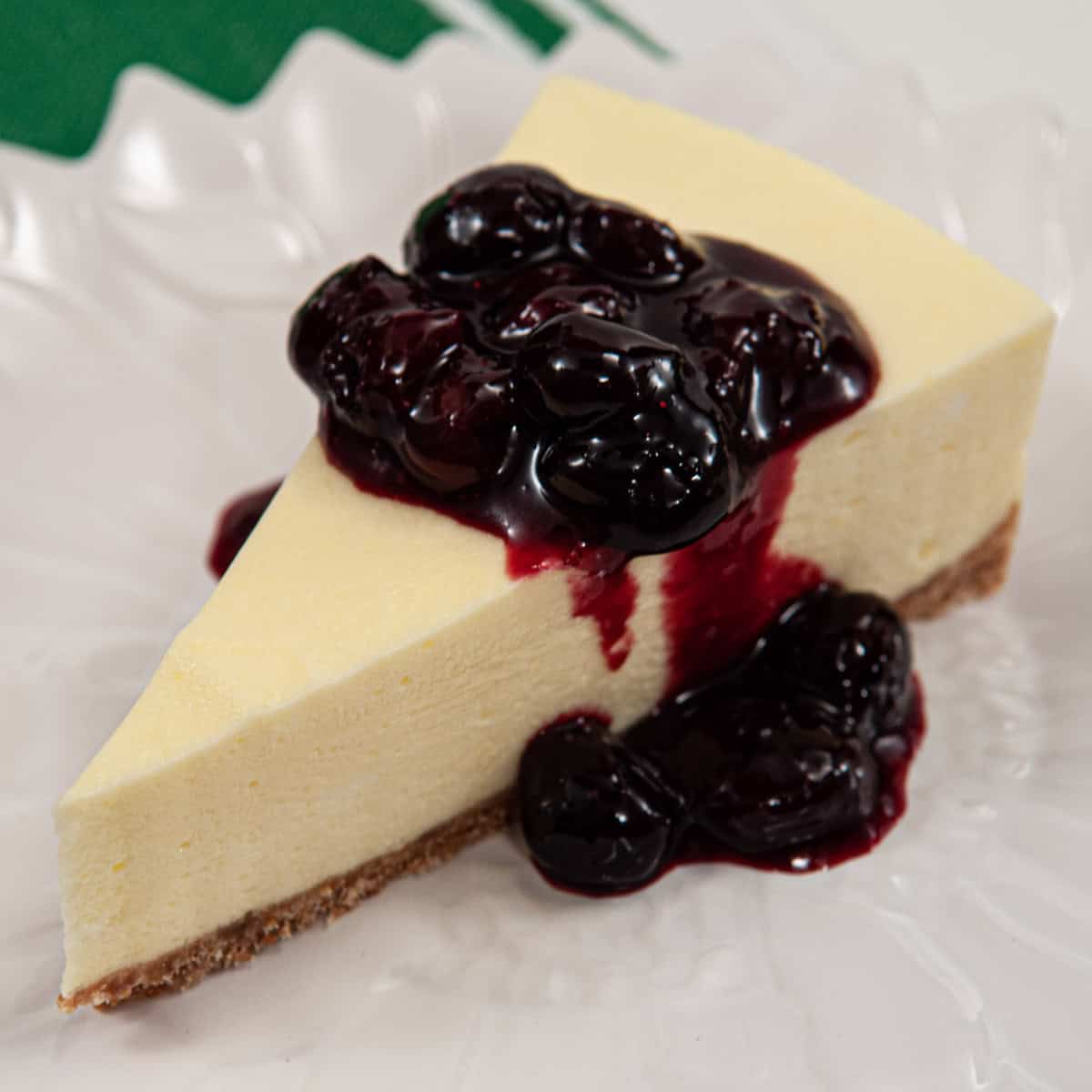 A slice of the Lemonade cake sits on a whit plate with a blueberry sauce.
