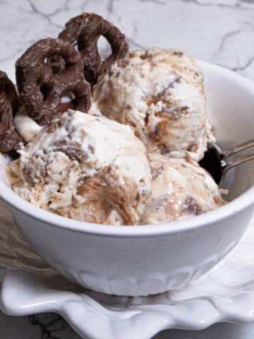 A bowl of No Churn Chocolate Pretzel Caramel Ice Cream shows the ice cream and a few chocolate pretzels.