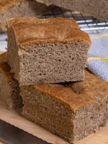 A stick of Lemon Pepper focaccia sits on a cutting board with a napkin and knife.