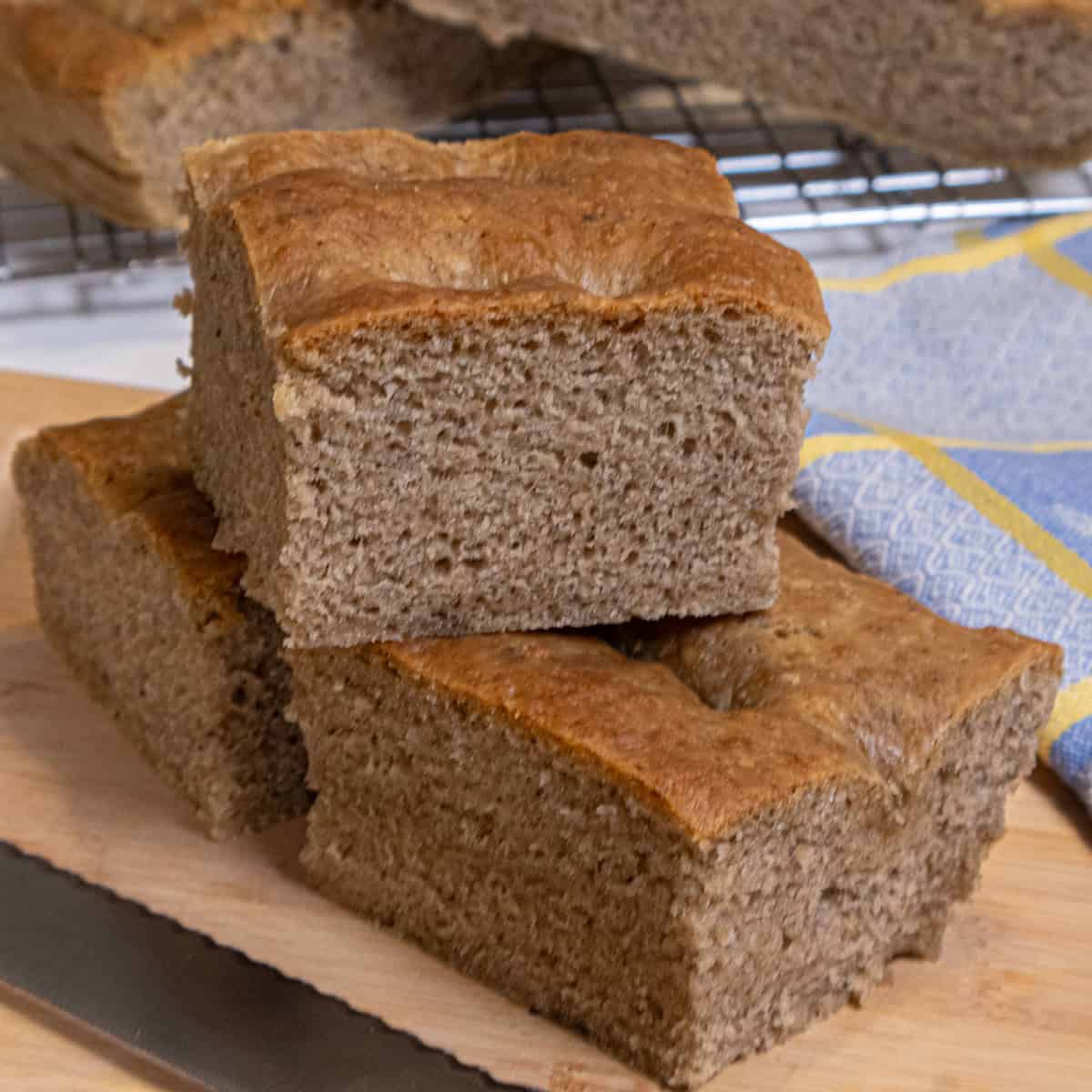 A stick of Lemon Pepper focaccia sits on a cutting board with a napkin and knife.
