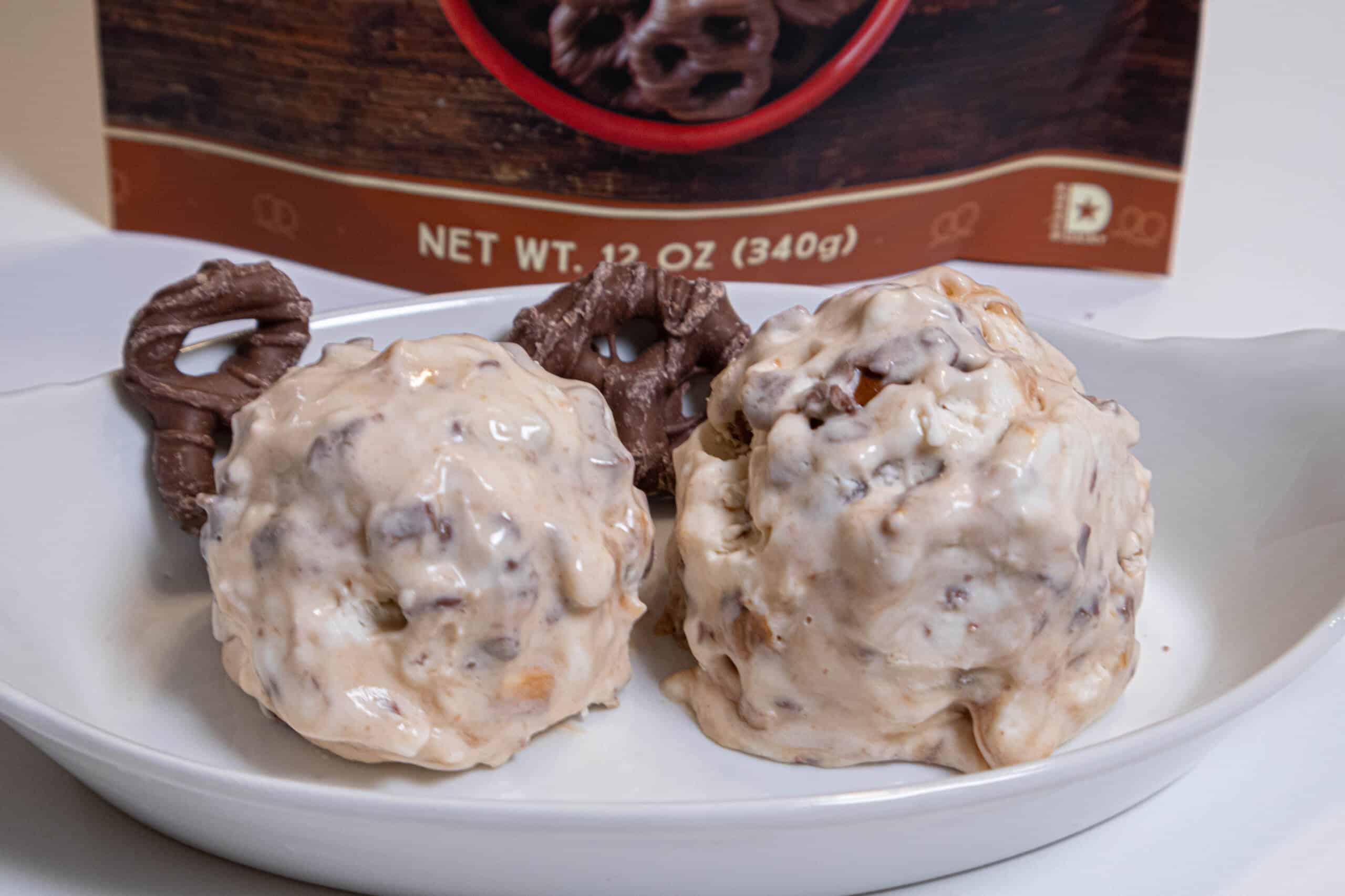 This photo shows 2 scoops of the Chocolate Pretzel Caramel Ice Cream in a dish with a few chocolate prezels and a bag of them in the background.