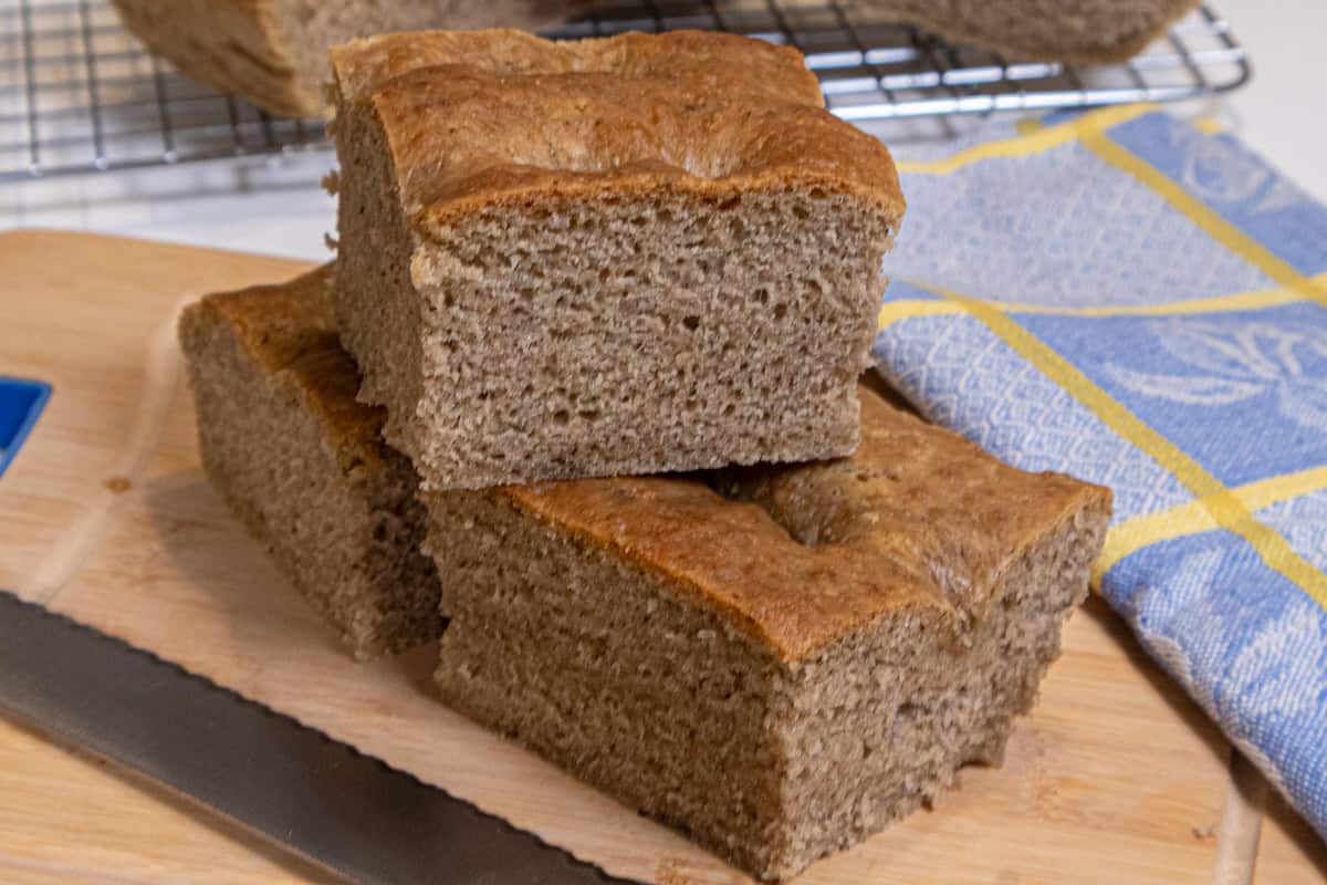 A stick of Lemon Pepper focaccia sits on a cutting board with a napkin and knife.