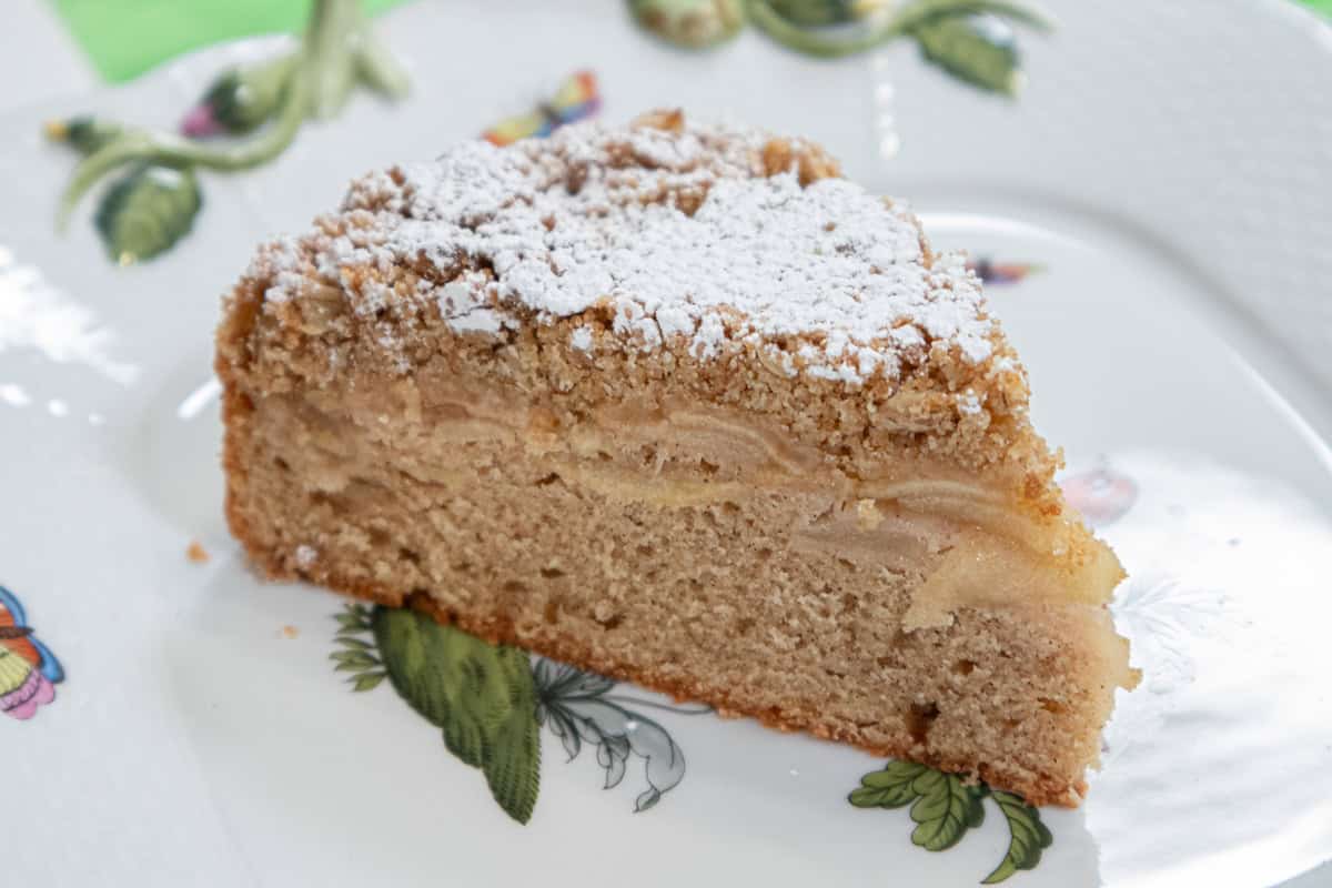 A slice of the Irish Apple Cake sits on a square plate decorated with in green leaves and the snakes of Ireland.